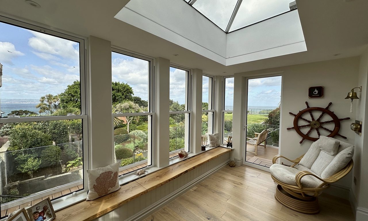 Bright room with a roof lantern, timber window seat and views across gardens to the sea
