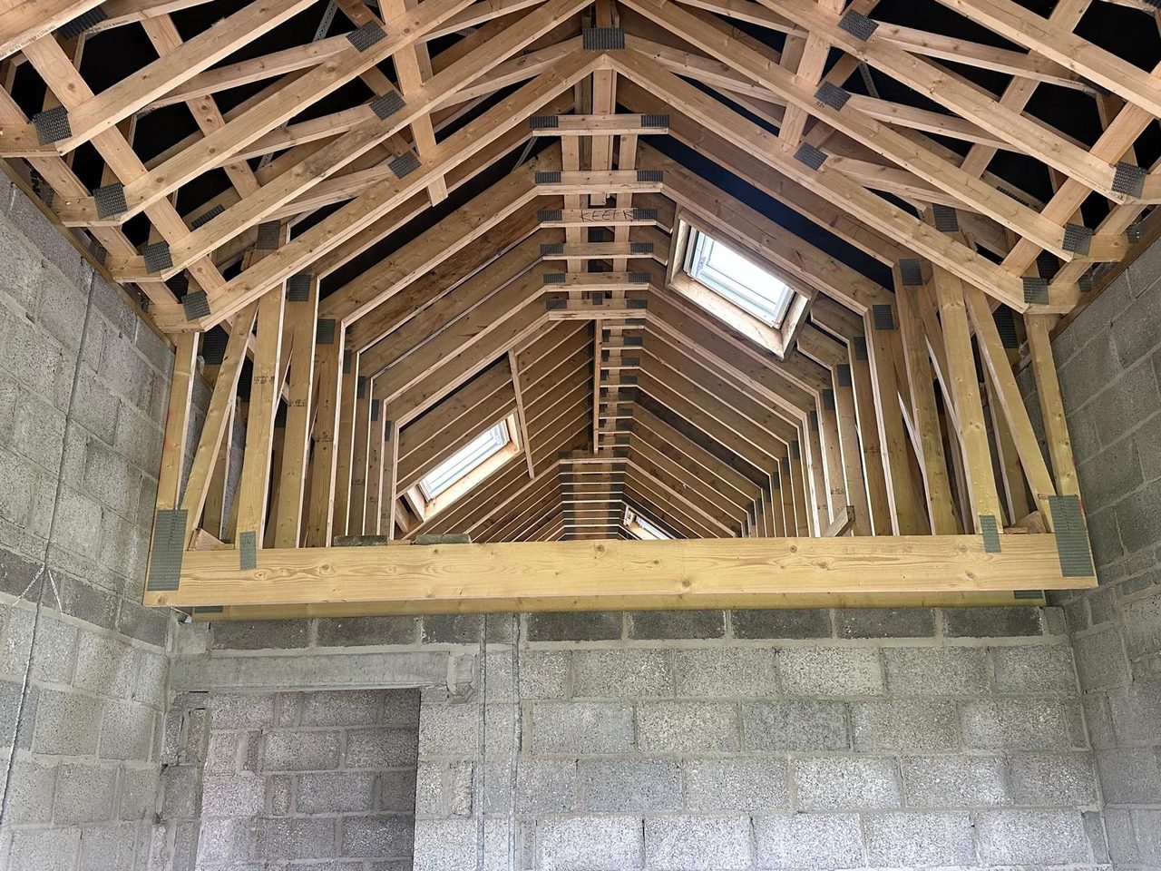 Timber roof trusses and rooflights above blockwork walls, seen from inside
