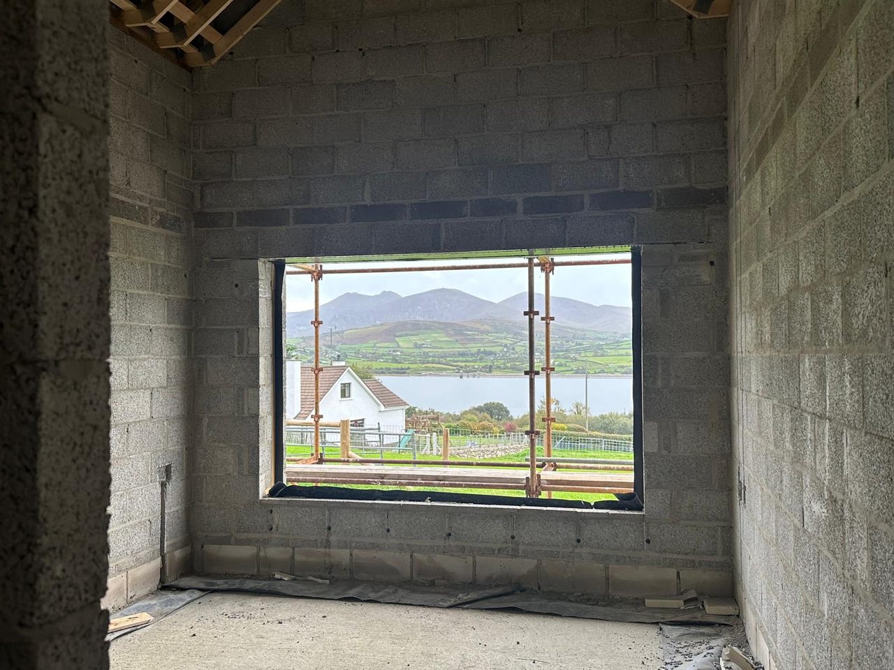Window opening in a blockwork room looking out over a lough to the Mourne Mountains