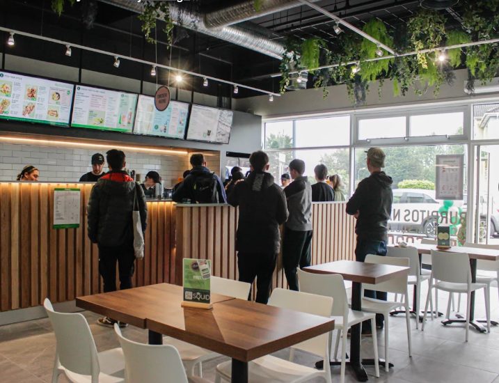 Customers at the counter beside timber tables and white chairs
